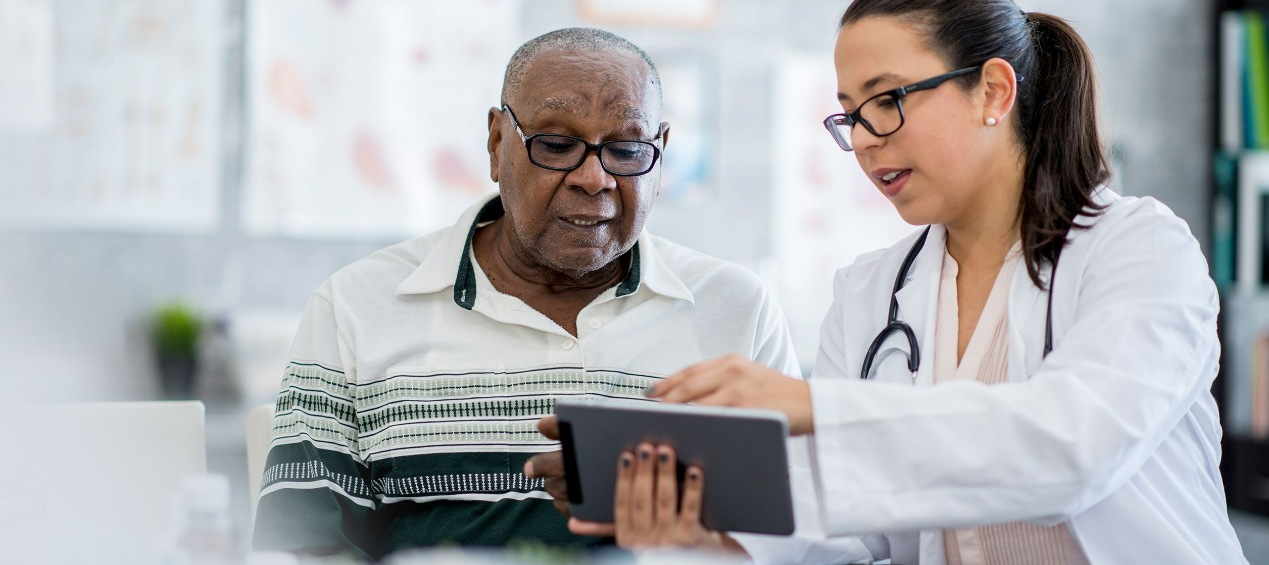 Senior man with female doctor looking at tablet
