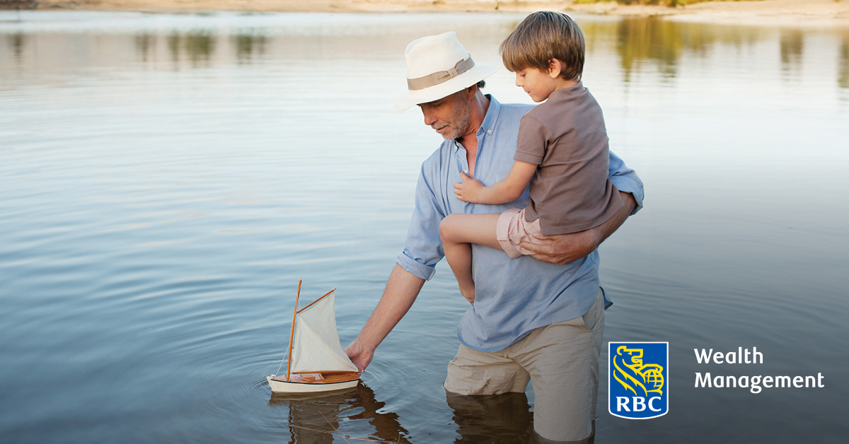 Man and boy playing with sailboat in pond