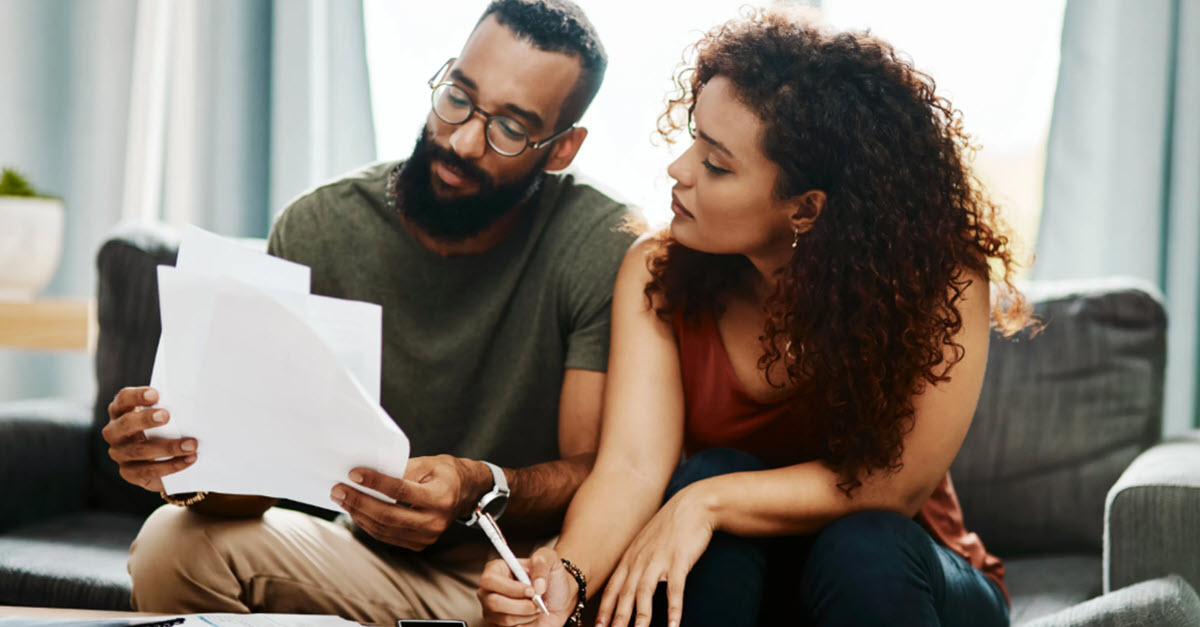Couple sitting on a couch looking at tax documents