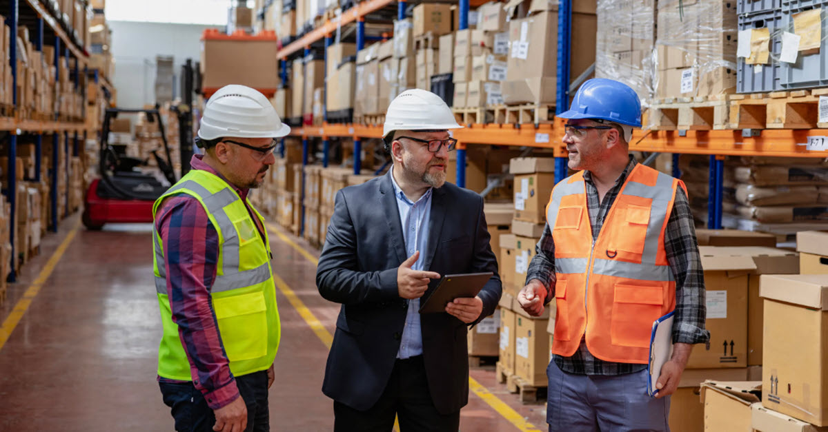 Three warehouse workers chatting in a warehouse