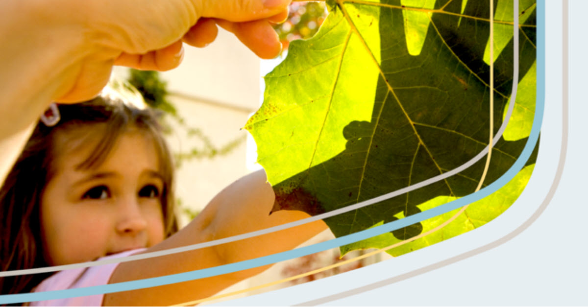 Parent showing their daughter a large leaf