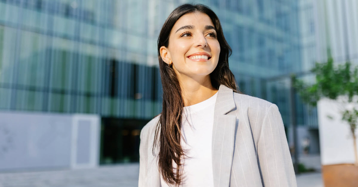 Young woman smiling outside in the sun in front of an office building